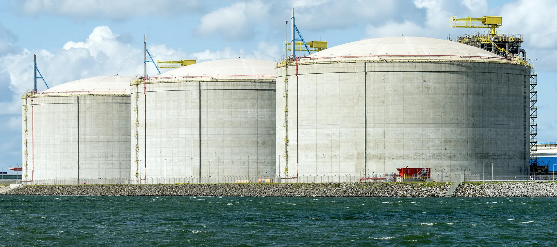 Vista de grandes tanques en un puerto utilizados en la industria del gas natural licuado.