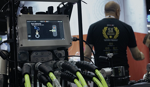 La bomba LIGHTNING PUMP Smart se muestra en una feria comercial con un técnico de HYTORC al fondo.